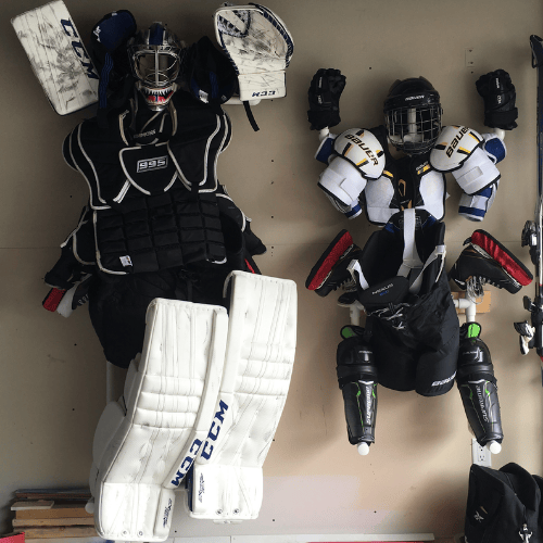 Hockey equipment hanging on a wall to air dry, including pads, helmet, and skates
